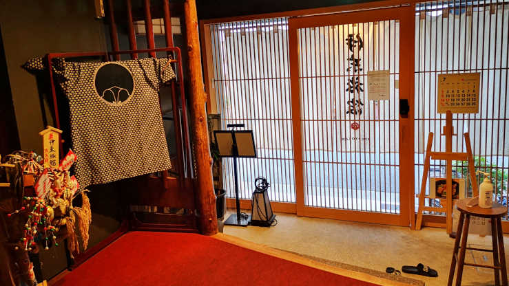 Entrance of a Tokyo ryokan with wooden sliding doors, tatami mats, onsen, and a calm, inviting ambiance