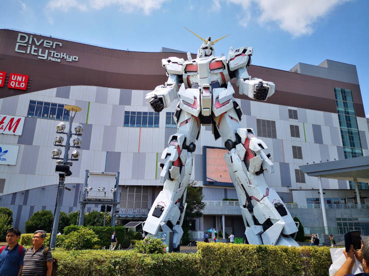 Full view of the Unicorn Gundam statue in Odaiba Tokyo with modern architecture around it