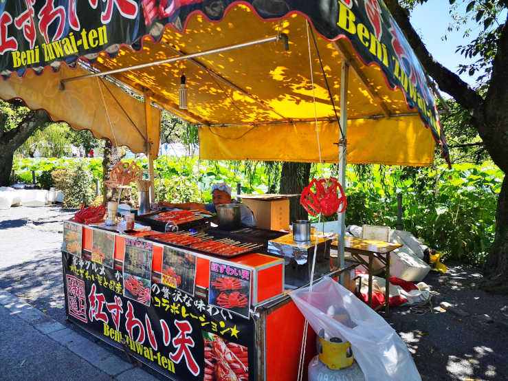 Makeshift street food booth in Ueno Park with customers and surrounding trees