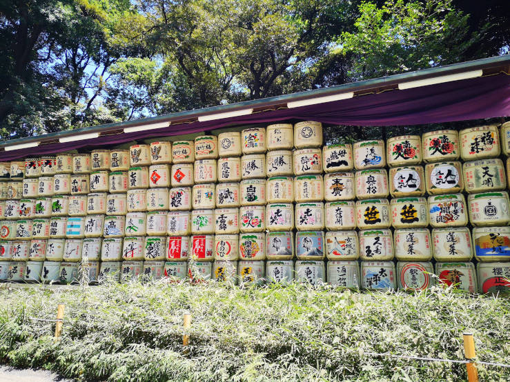 Row of traditional rice barrels displayed along the path to Meiji Jingu Shrine in Tokyo, symbolising sake offerings to the shrine