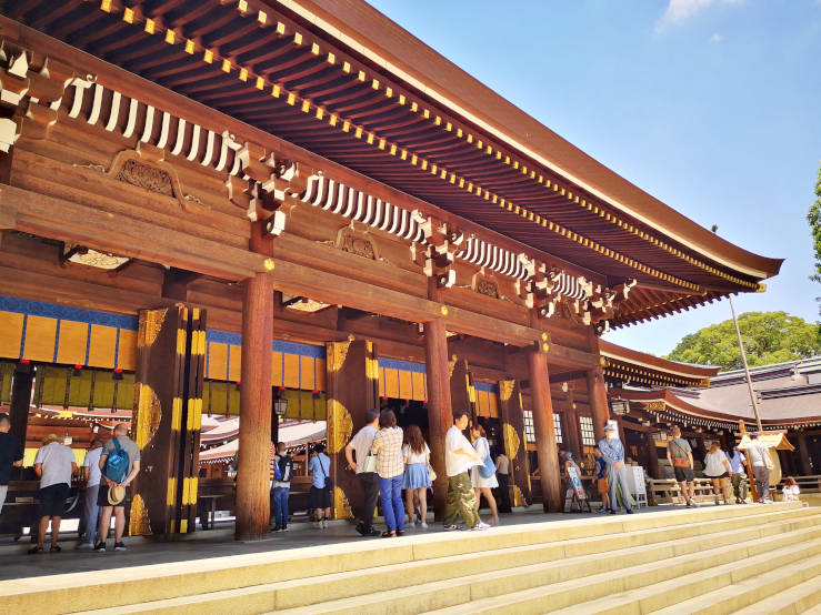 Visitors standing at the top of stone steps in front of a shrine building at Meiji Jingu in Tokyo