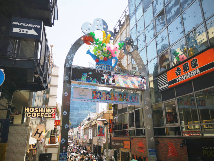 Takeshita Street entrance in Harajuku Tokyo with colourful arch and busy shopping street