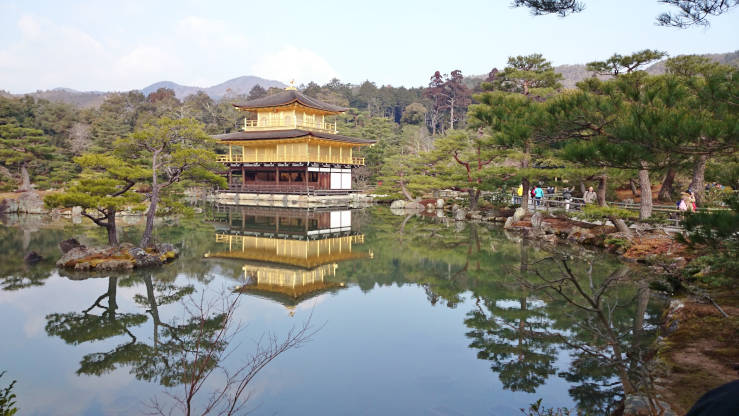 Kinkakuji Temple Golden Pavilion reflected in the calm pond in Kyoto surrounded by trees and traditional Japanese garden scenery