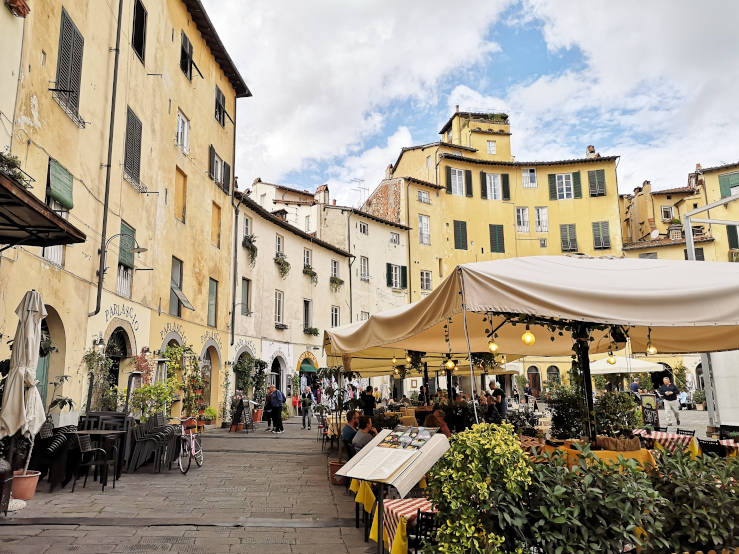 Piazza dell'Anfiteatro in Lucca with curved yellow buildings and outdoor restaurant