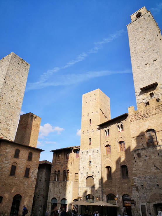Four medieval towers rising above San Gimignano against the Tuscan sky